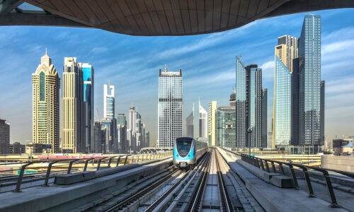 Driverless metro in Dubai approaching the subway station with futuristic city skyline on background in Dubai, United Arab Emirates, Persian Gulf.